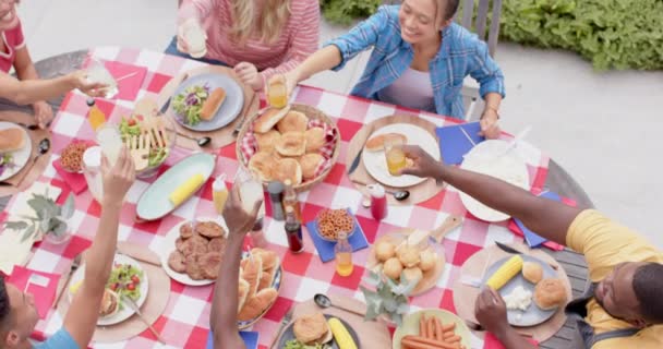 庭でディナーテーブルで乾杯する友人の多種多様なグループ 遅い動き 食べ物 お祝い トータルネス ライフスタイル 家庭生活 変わらない — ストック動画