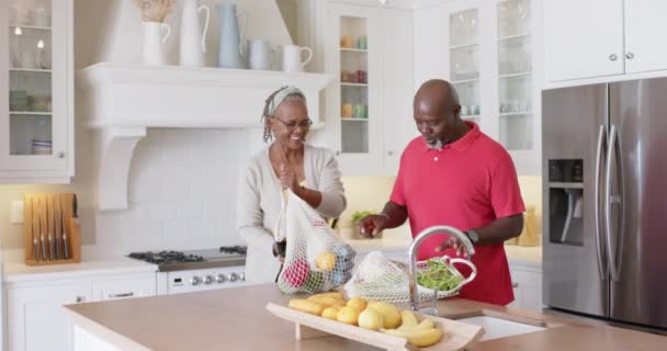 Heureux Couple Afro Américain Senior Déballer Les Courses Dans Cuisine — Video
