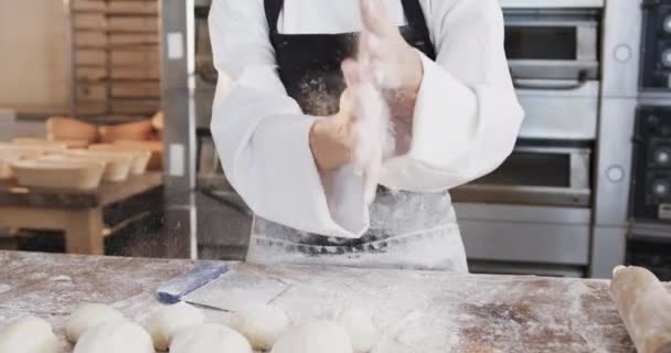ベーカリーキッチンで働くアジアの女性パン職人は スローモーションで手から小麦粉をブラッシング 中小企業 ベーキング パン屋 変更なし — ストック動画