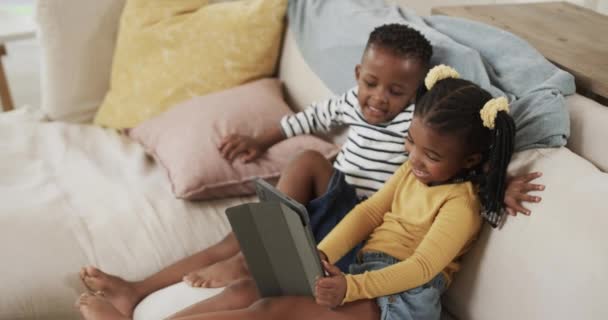 快乐的非洲裔美国兄弟姐妹在家里的沙发上用平板电脑放松一下 慢动作 闲暇时间 生活方式和家庭生活 — 图库视频影像