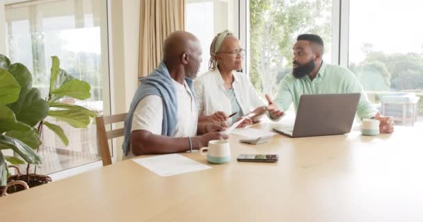 アフリカ系アメリカ人の財務顧問と高齢者のカップルが自宅で話して スローモーション コミュニケーション アドバイス 国内生活とシニアライフスタイル 変更なし — ストック動画