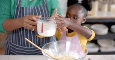 Mutlu Afro-Amerikan anne ve kızı mutfakta hamur hazırlıyor, ağır çekimde. Yaşam tarzı, aile, birliktelik, yemek, aşçılık ve ev hayatı, değişmemiş..