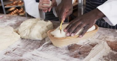 Fırın mutfağında çalışan çeşitli fırıncılar ekmek hamurunu yavaş çekimde kesiyorlar. Takım çalışması, yemek, küçük işletme, fırın ve çalışma, değiştirilmemiş.