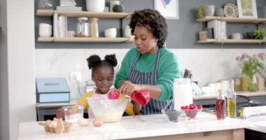 Mutlu Afro-Amerikan anne ve kızı mutfakta hamur hazırlıyor, ağır çekimde. Yaşam tarzı, aile, birliktelik, yemek, aşçılık ve ev hayatı, değişmemiş..