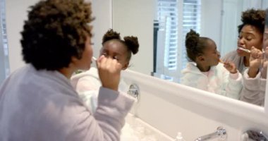 Afro-Amerikan anne ve kızının banyoda dişlerini fırçalaması, ağır çekim. Yaşam tarzı, kişisel bakım, hijyen ve ev hayatı, değişmemiş..