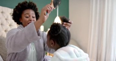 Mutlu Afro-Amerikan anneler yatak odasında kızlarının saçlarını tarıyor, ağır çekimde. Yaşam tarzı, aile, birliktelik, özgüven ve ev hayatı, değişmemiş..