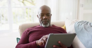 Afrika kökenli Amerikalı son sınıf öğrencisi evde tablet kullanıyor, ağır çekimde. Emeklilik, ev hayatı, iletişim ve kıdemli yaşam tarzı, değişmedi..