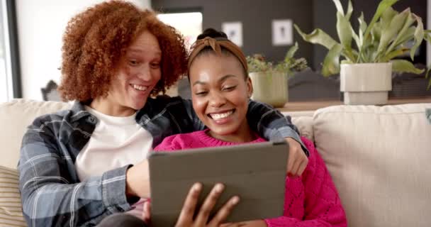 Szczęśliwa Zróżnicowana Para Obejmująca Używając Tabletu Rozmawiając Kanapie Salonie Zwolnionym — Wideo stockowe