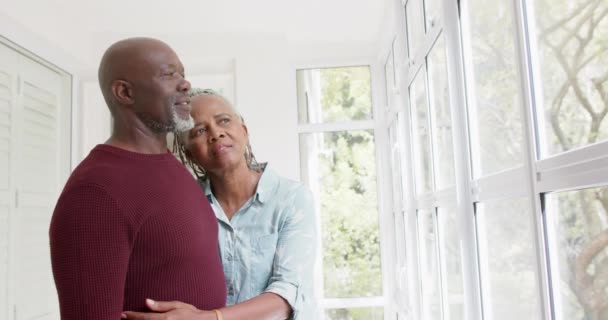 Casal Afro Americano Sênior Atencioso Abraçando Olhando Pela Janela Casa — Vídeo de Stock