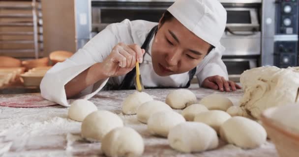 Focused Asian Female Baker Working Bakery Kitchen Cutting Dough Rolls — Stock Video