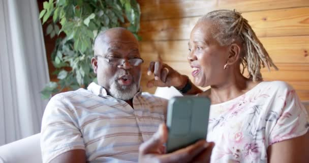 Szczęśliwa Starsza Afrykańska Para Używa Smartfona Siedzącego Kanapie Domu Zwolnionym — Wideo stockowe