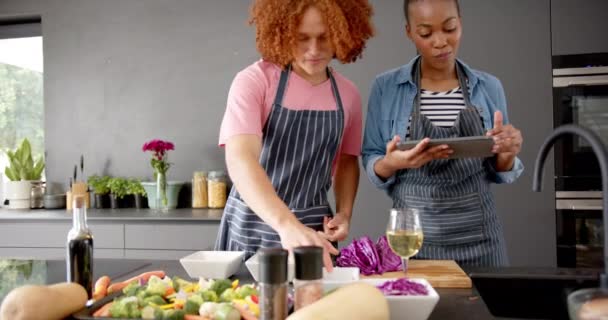 野菜を準備し 台所でタブレットを使用してエプロンで幸せな多様なカップル スローモーションで 一緒に レシピと国内生活 変更なし — ストック動画