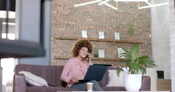 Happy Biracial Casual Businesswoman Using Laptop Talking Phone Couch Office — Video