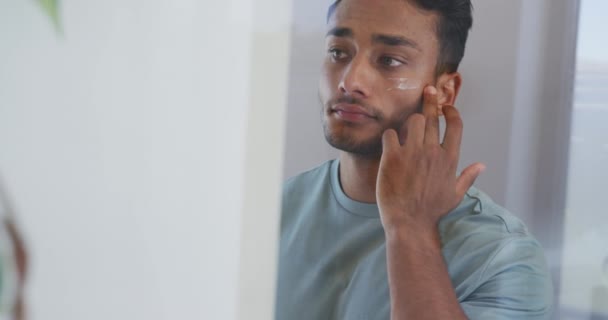 Biracial Man Tittar Spegeln Och Tillämpa Ansiktskräm Badrummet Slow Motion — Stockvideo