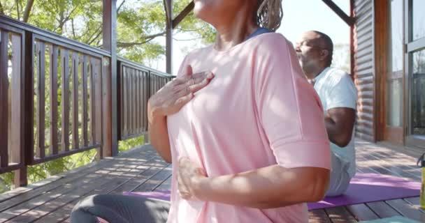 以资深非洲裔夫妇为重点 在阳光普照的阳台上练习瑜伽 动作缓慢 老年人的生活方式 自然福利和退休 — 图库视频影像