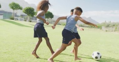 Sahada çıplak ayakla futbol oynayan üç Afro-Amerikan öğrencinin videosu. Eğitim, çocukluk, kapsayıcılık, sağlık, spor, ilkokul ve öğrenim kavramı.