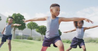 Üç Afro-Amerikan öğrencinin dışarıda yoga yaparken çekilmiş videosu. Eğitim, çocukluk, kapsayıcılık, sağlık, spor, ilkokul ve öğrenim kavramı.