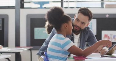 Çeşitli erkek öğretmenler ve okul sınıfında tablet kullanan mutlu öğrenciler. Eğitim, kapsayıcılık, ilkokul ve öğrenim kavramı.