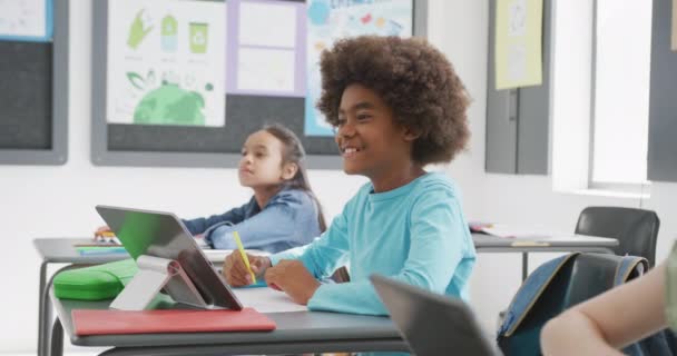 Video Van Gelukkige Diverse Schoolkinderen Zitten Aan Bureaus Met Tabletten — Stockvideo