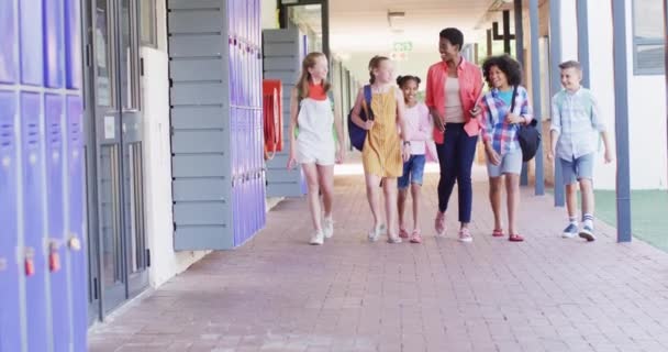 多様な女性教師と幸せな学校の子供たちが学校を歩いています コミュニティ 小学校 学習コンセプト — ストック動画