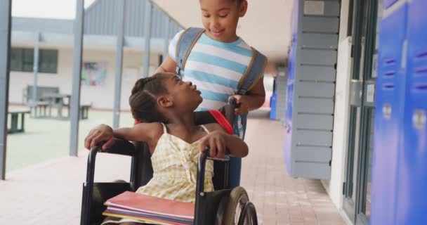 Видео Двух Счастливых Разноплановых Школьниц Одна Толкает Другую Инвалидной Коляске — стоковое видео