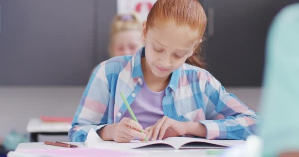 Valkoihoisen Koulutytön Muotokuva Istuu Pöydän Ääressä Hymyillen Kirjoittaen Luokkahuoneessa Koulutus — kuvapankkivideo
