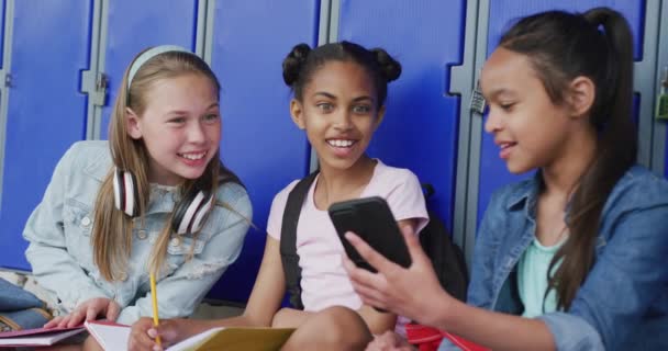 Nagranie Trzech Szczęśliwych Różnorodnych Uczennic Patrzących Smartfona Siedzących Przy Szafkach — Wideo stockowe