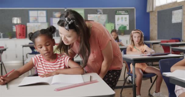 Ευτυχής Ποικιλόμορφη Δασκάλα Που Βοηθάει Μαθήτρια Στο Γραφείο Στην Τάξη — Αρχείο Βίντεο