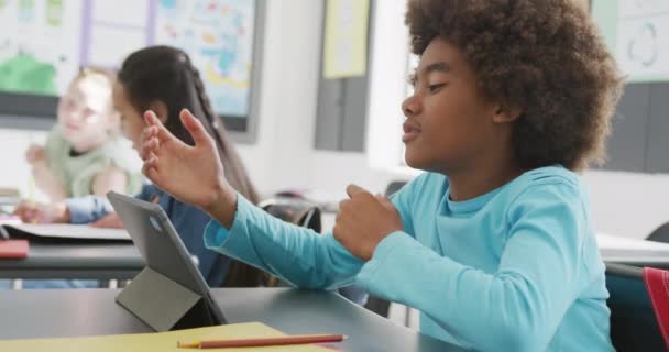 クラスでタブレットを使って机の上に座っている イライラしたアフリカ系アメリカ人のボーイのビデオ コピースペース 幼少期 テクノロジー 小学校 学習コンセプト — ストック動画