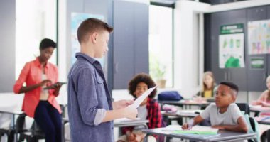 Çeşitli bayan öğretmenler ve okul sıralarında okuyan mutlu öğrenciler. Eğitim, kapsayıcılık, ilkokul ve öğrenim kavramı.