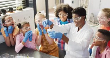 Çeşitli bayan öğretmenler ve mutlu okul çocukları okulda fen dersi alıyorlar. Eğitim, kapsayıcılık, ilkokul ve öğrenim kavramı.