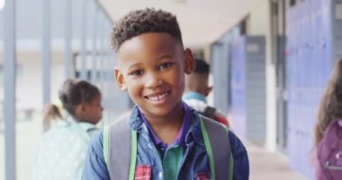 Okul koridorunda yürüyen mutlu Afro-Amerikan okul çocuğunun portresi. Eğitim, kapsayıcılık, ilkokul ve öğrenim kavramı.