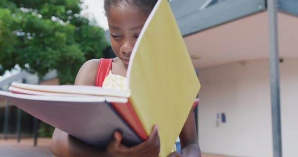 Wideo Przedstawiające Szczęśliwą Afrykańską Uczennicę Przeglądającą Swoje Książki Poza Szkołą — Wideo stockowe