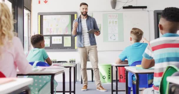 Mångsidig Manlig Lärare Och Glada Skolbarn Vid Skrivbordet Klassrummet Utbildning — Stockvideo