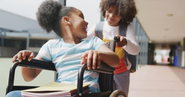 Nagranie Dwojga Szczęśliwych Uczniów Chłopca Pchającego Dziewczynę Wózku Inwalidzkim Korytarzu — Wideo stockowe