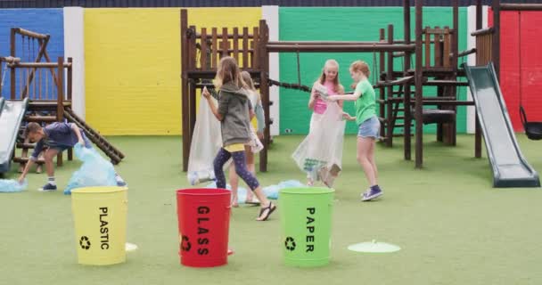 学校の遊び場のバッグと一緒に廃棄物を分離するハッピーな白人学校の子供たち コミュニティ 小学校 学習コンセプト — ストック動画