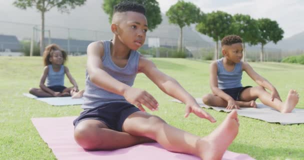 三个非洲裔美国学童坐在室外练习瑜伽的录像 包容性 小学教育和学习概念 — 图库视频影像