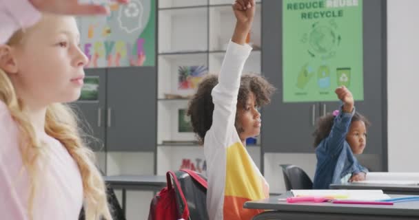 Video Erilaisista Koululaisista Jotka Istuvat Pöydillä Nostamassa Käsiään Luokassa Koulutus — kuvapankkivideo