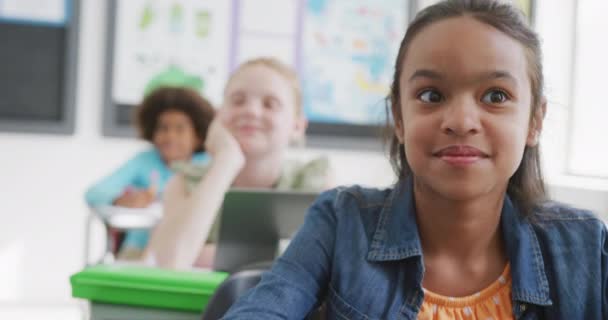 Video Hymyilevä Kaksirotuinen Koulutyttö Istuu Pöydän Ääressä Käyttäen Tabletti Luokassa — kuvapankkivideo