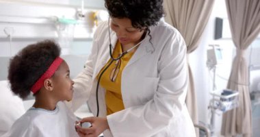 Hastane odasında steteskop kullanan Afrika kökenli Amerikalı kadın doktor, ağır çekimde. İlaç, sağlık hizmetleri, çocukluk ve hastane, değiştirilmemiş.