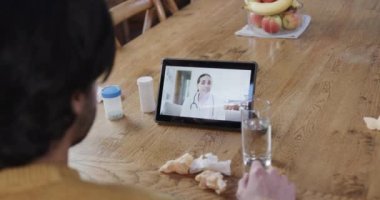 Beyaz adam ekranda kadın doktorla birlikte tablet kullanarak video görüşmesi yapıyor, yavaş çekim. Tıbbi hizmetler, iletişim, teletıp ve sağlık hizmetleri, değiştirilmemiş.