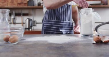 Kafkasyalı bir adamın mutfakta ekmek hamuru hazırlaması, ağır çekim. Sağlıklı yaşam tarzı, yemek, yemek pişirme ve ev yaşamında değişiklik yok..