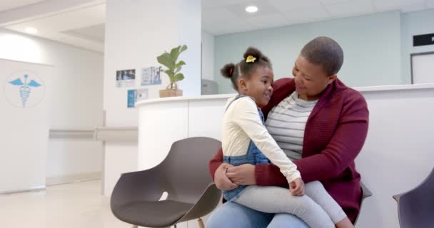 Šťastná Africká Americká Matka Která Drží Dceru Kolenou Nemocniční Čekárně — Stock video