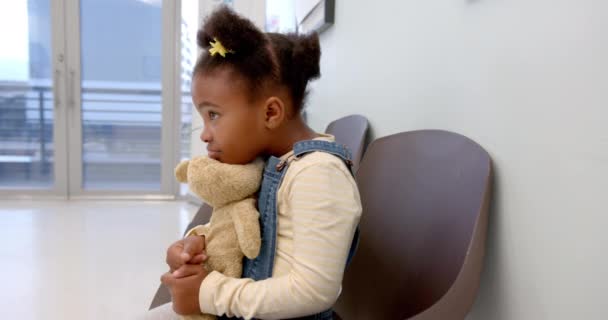 Happy African American Girl Sitting Hospital Waiting Room Holding Mascot — Vídeo de Stock