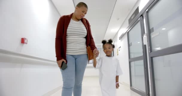 African American Mother Daughter Hospital Gown Holding Hands Walking Corridor — стоковое видео