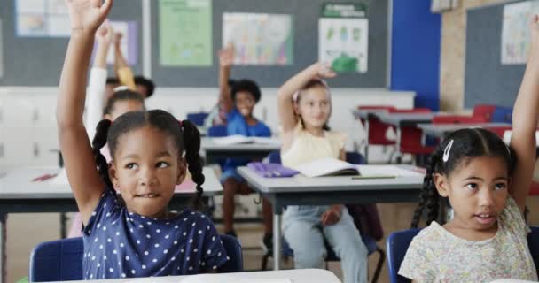 Onnellinen Monipuolinen Koululaiset Pöydillä Nostaa Kätensä Peruskoulun Luokkahuoneessa Hidastettuna Koulu — kuvapankkivideo