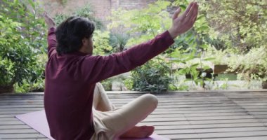 Beyaz adam terasta yoga meditasyonu uyguluyor. Güneşli doğada, kopyalama alanında, ağır çekimde. Sağlıklı yaşam tarzı, doğada refah, egzersiz, zindelik ve ev hayatı, değişmemiş..