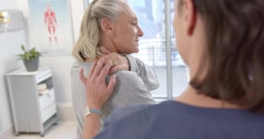 Caucasian female physiotherapist massaging back of female senior patient at rehab center. Physiotherapy rehabilitation and medical healthcare concept