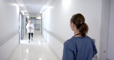 Happy caucasian female doctors greeting each other in hospital corridor, slow motion. Medicine, healthcare services, disability, communication and hospital, unaltered.