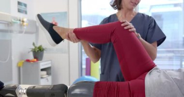 Caucasian female physiotherapist stretching leg of female patient at rehab center. Prosthetics, physiotherapy rehabilitation and medical healthcare concept